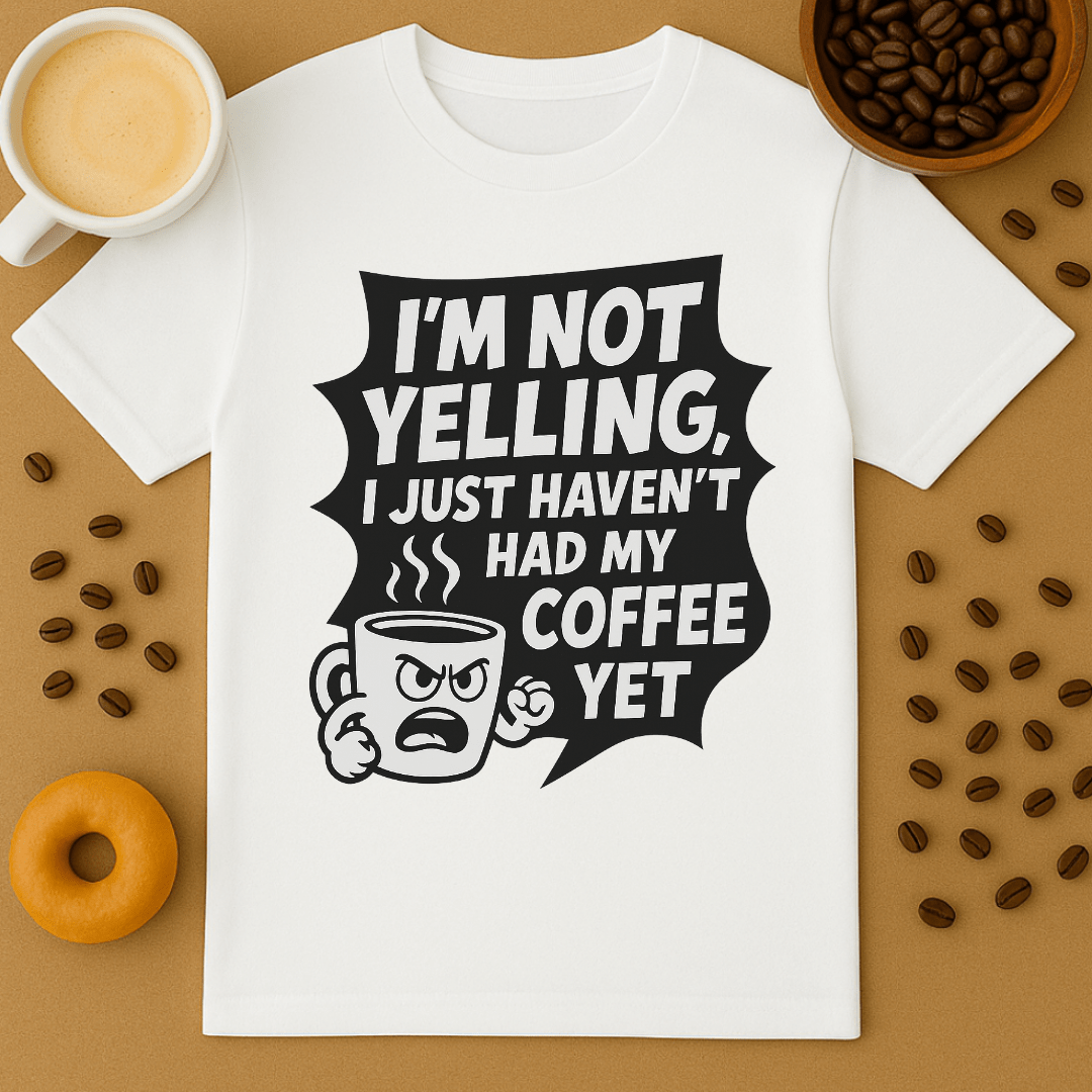 White t-shirt with coffee-themed graphic and text on a brown background with coffee beans and a donut.