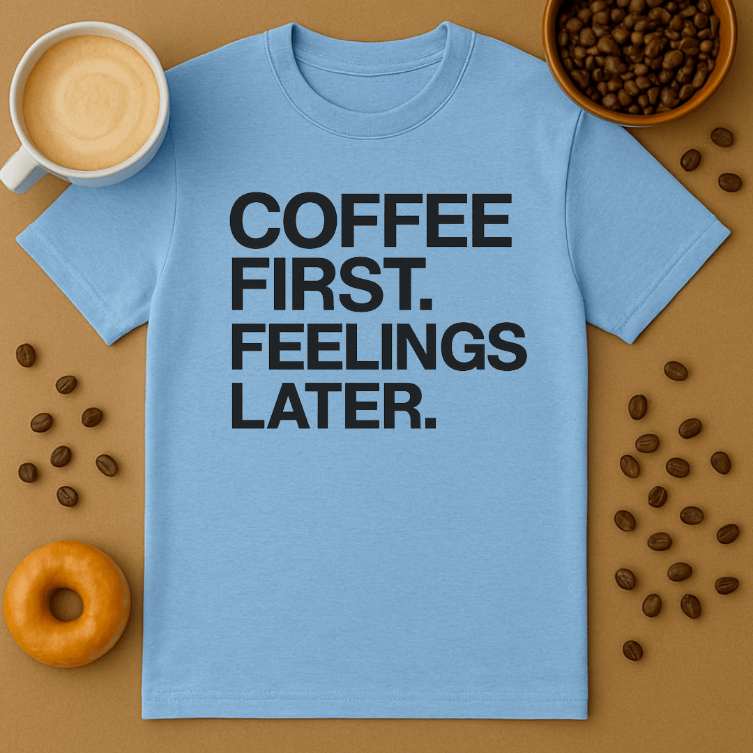 Blue t-shirt with 'Coffee First, Feelings Later' text on a brown background with coffee beans and a donut.
