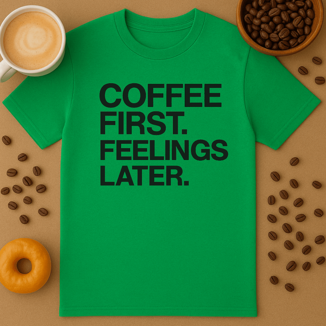 Green t-shirt with 'Coffee First, Feelings Later' text on a brown surface with coffee beans and a cup of coffee.
