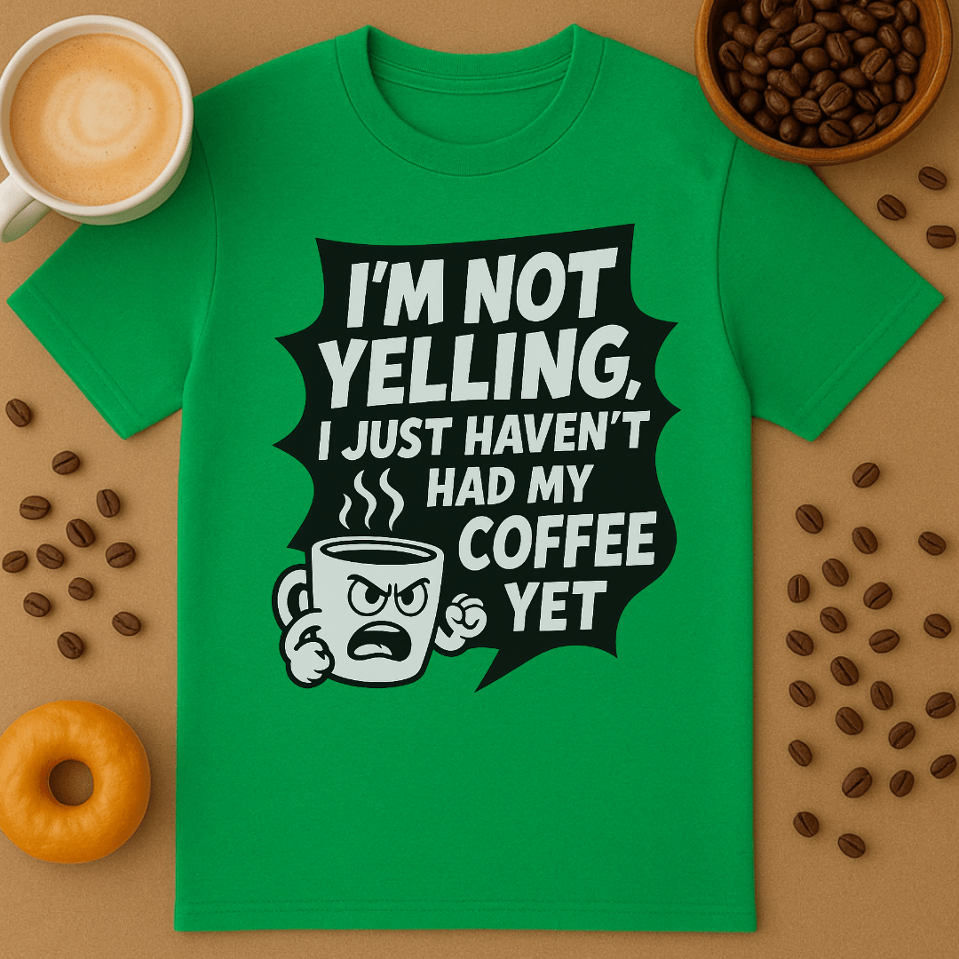 Green t-shirt with coffee-themed graphic and text on a brown surface with coffee beans and a cup.