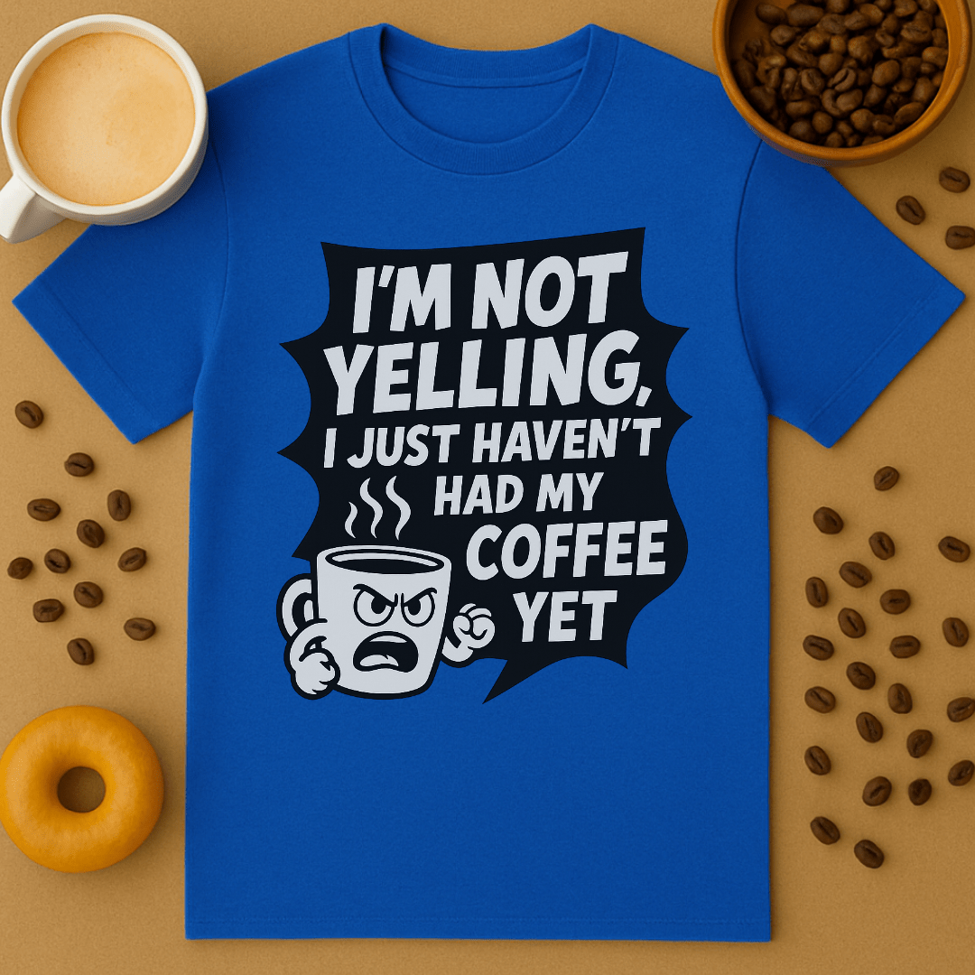 Blue t-shirt with coffee-themed graphic and text on a brown surface with coffee beans and a cup.