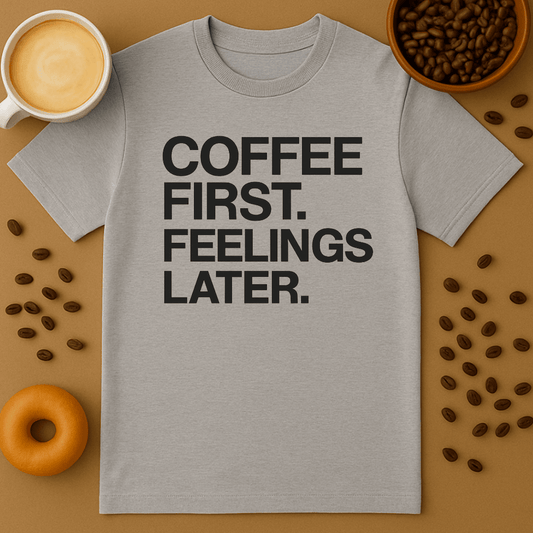 Gray t-shirt with 'Coffee First, Feelings Later' text on a brown background with coffee beans and a cup of coffee.